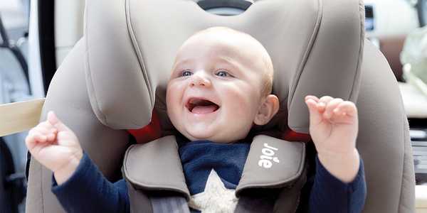 Close-up picture of a smiling baby in a car seat.